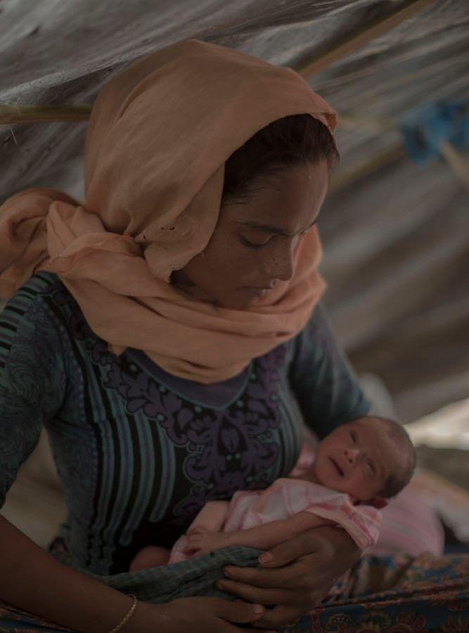 Rehana Begum, 20 år gammal, med sin nyfödda dotter. Hon födde även en son, som dog strax efter födseln. Han begravdes i en omärkt grav i leran bredvid deras tält i lägret. Bild: Aj Ghani/Röda Korset