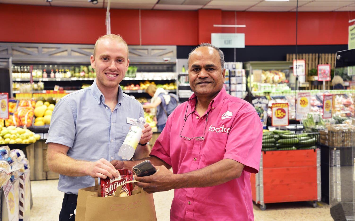 Butikschefen Niclas Sardellis har packat en leverans som Nadeem Ahmed, så kallad ”kapten” på Foodora, ska ta med.