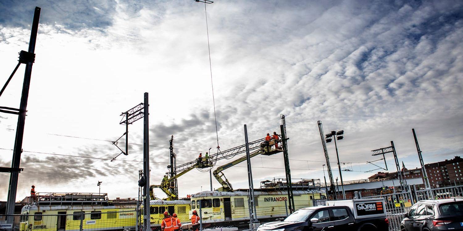 Ombyggnationen vid Olskroken har pågått i fyra år – i bland med hjälp från luften. Här, under påsken 2021, ska en helikopter lyfta av kontaktledningar från de metallbågar som reser sig över spåren.